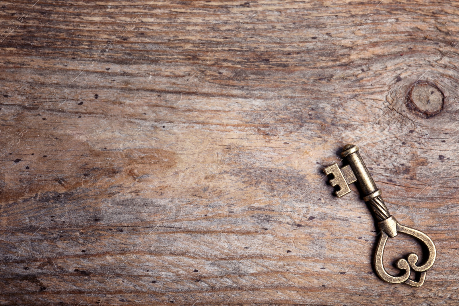 Photo of Old vintage key on wooden background, top view with space for text