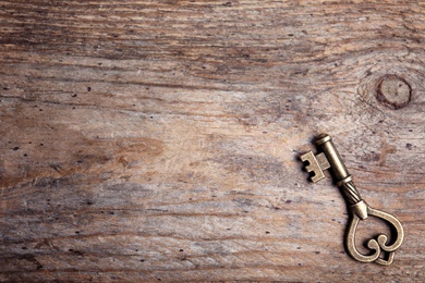 Photo of Old vintage key on wooden background, top view with space for text