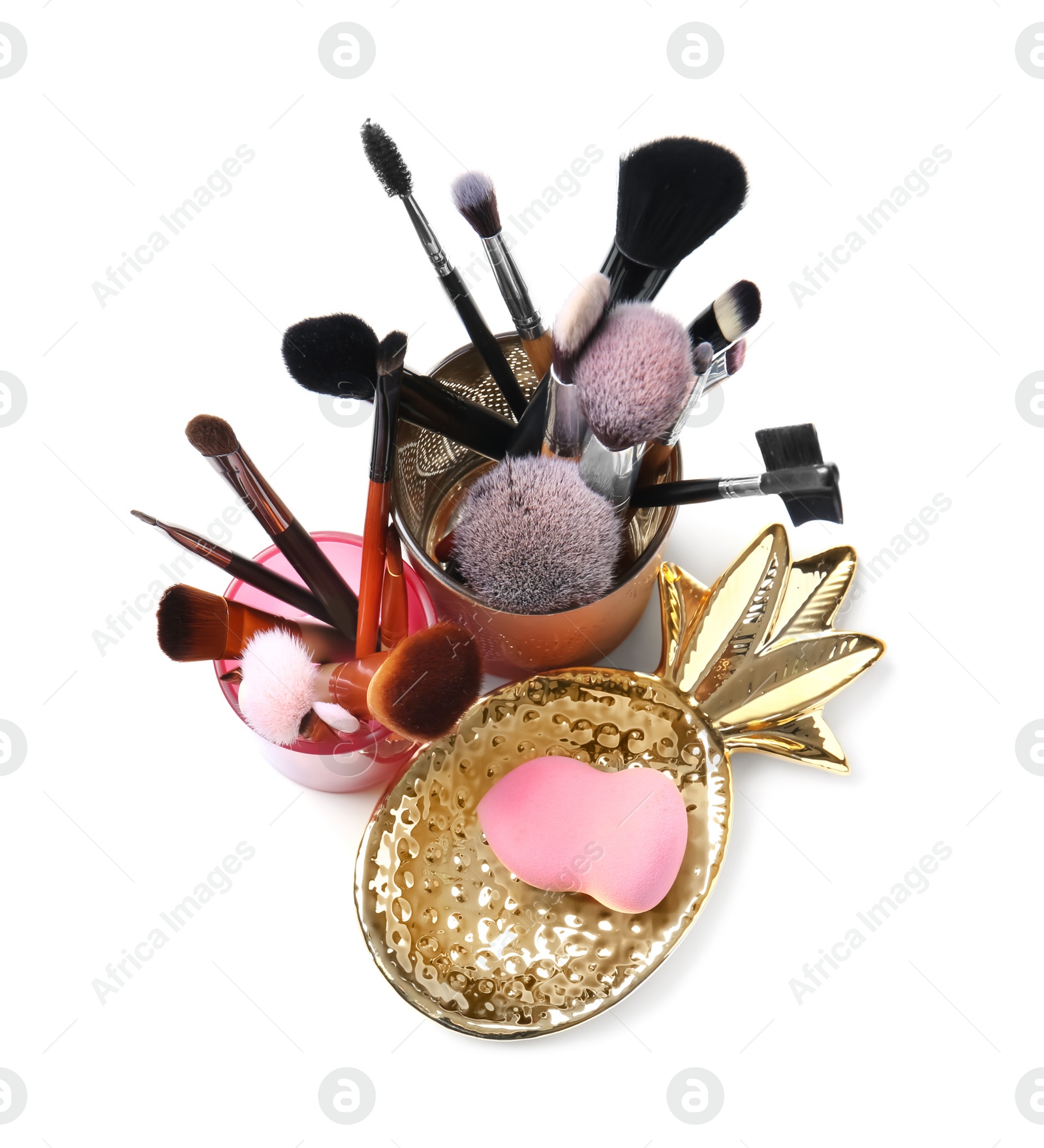 Photo of Holders with makeup brushes and sponge of professional artist on white background