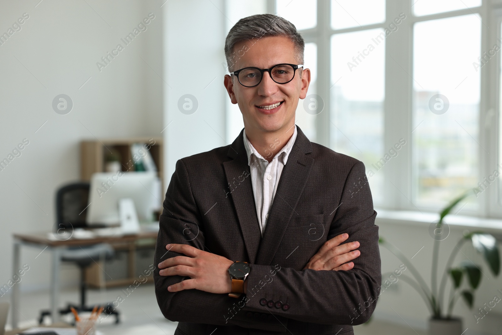 Photo of Happy man with crossed arms in office