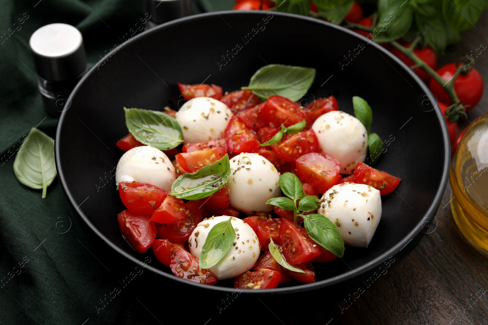 Photo of Tasty salad Caprese with tomatoes, mozzarella balls and basil on wooden table, closeup