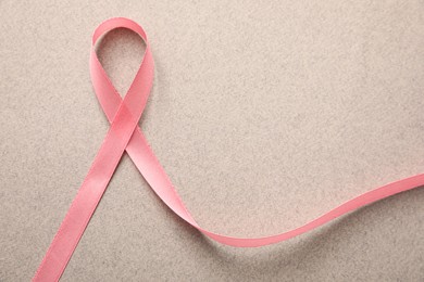 Pink ribbon on grey background, top view. Breast cancer awareness concept