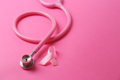 Photo of Pink ribbon with stethoscope on color background, space for text. Breast cancer concept