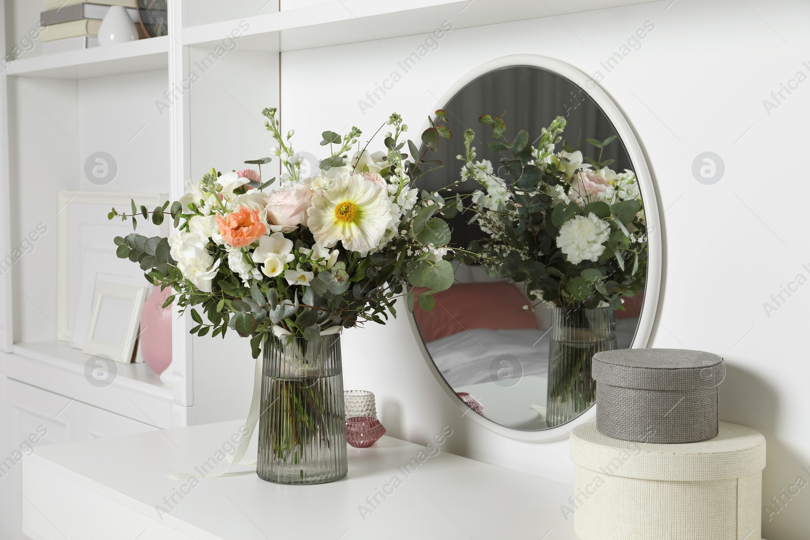 Photo of Bouquet of beautiful flowers on white table near mirror indoors