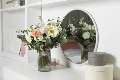 Bouquet of beautiful flowers on white table near mirror indoors