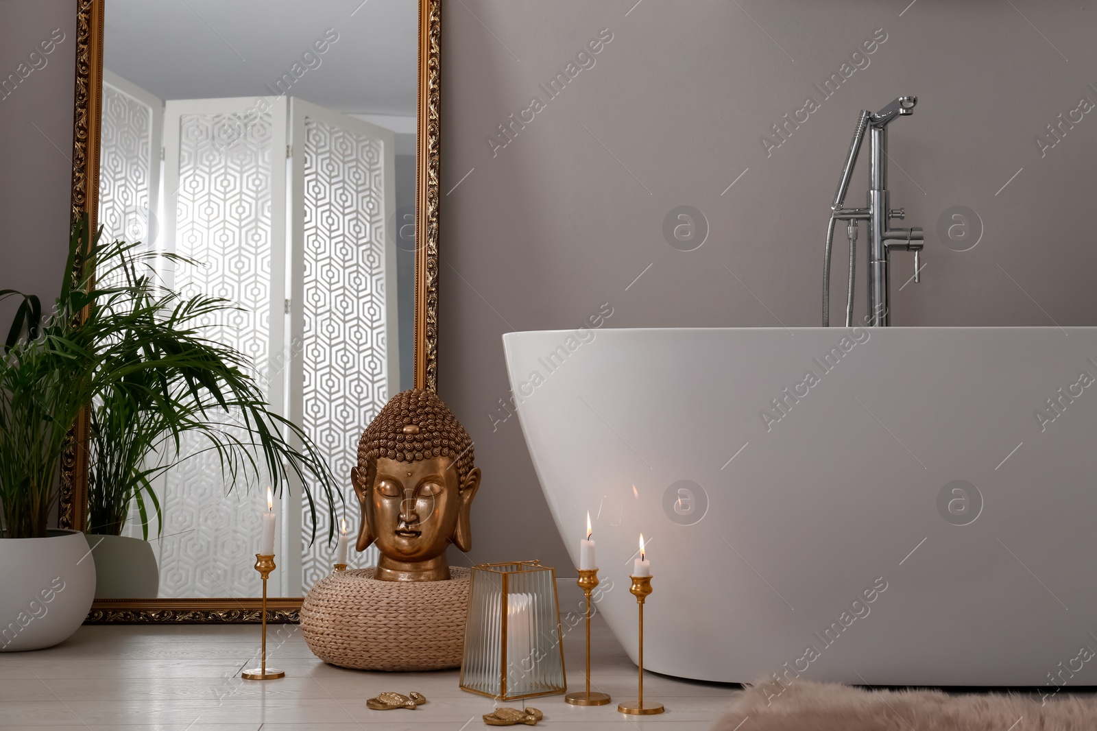 Photo of Bathroom interior with golden Buddha sculpture and modern white tub