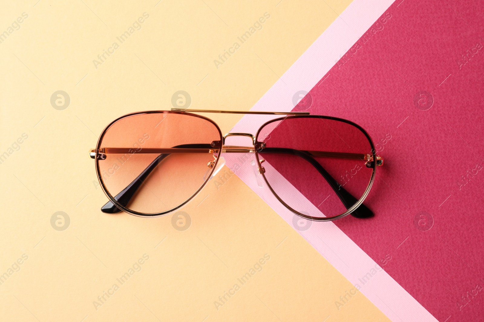 Photo of Stylish sunglasses on color background, top view