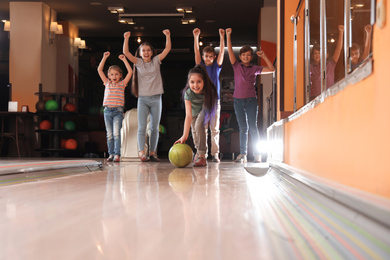 Girl throwing ball and spending time with friends in bowling club