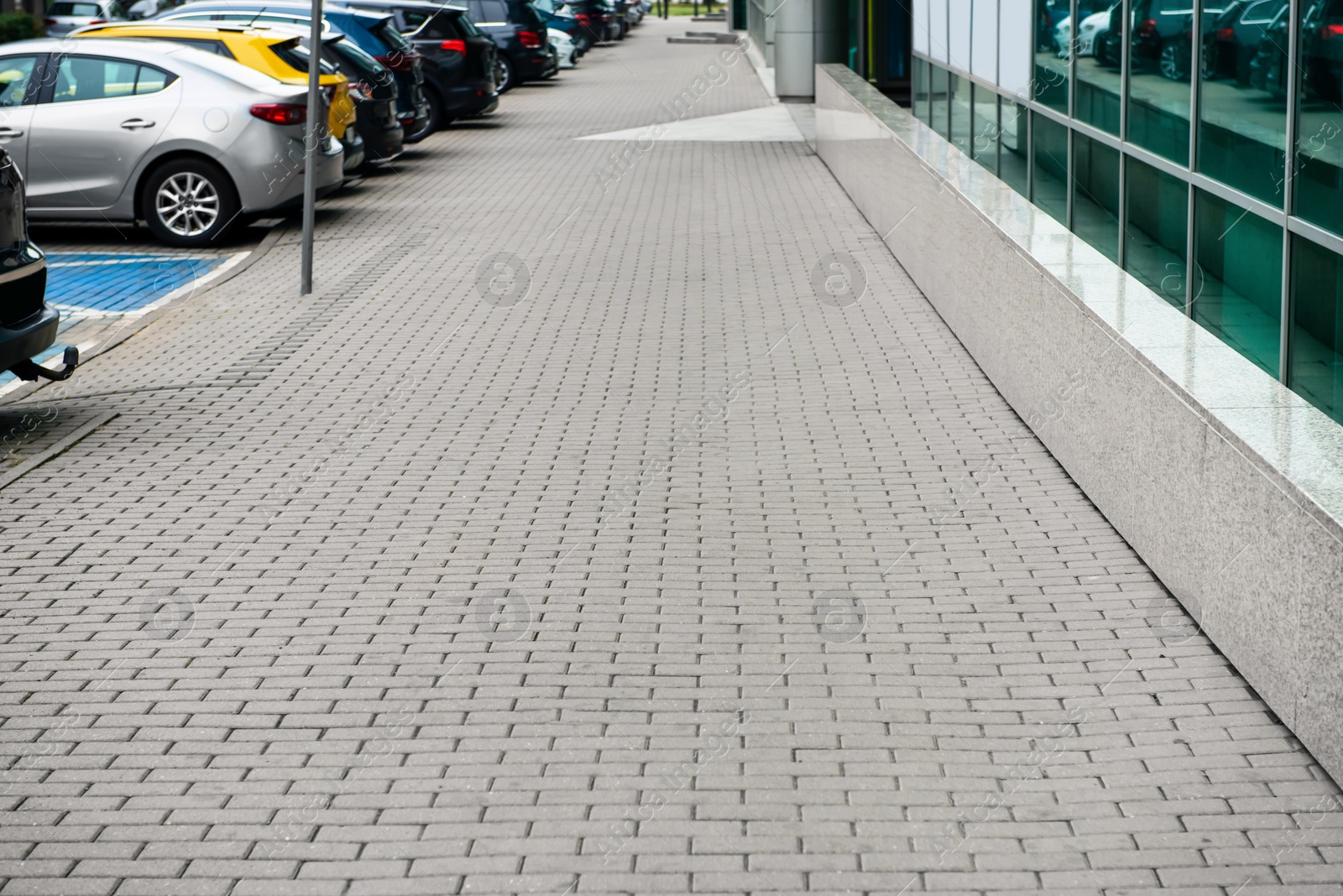 Photo of Sidewalk path near cars on city street. Footpath covering