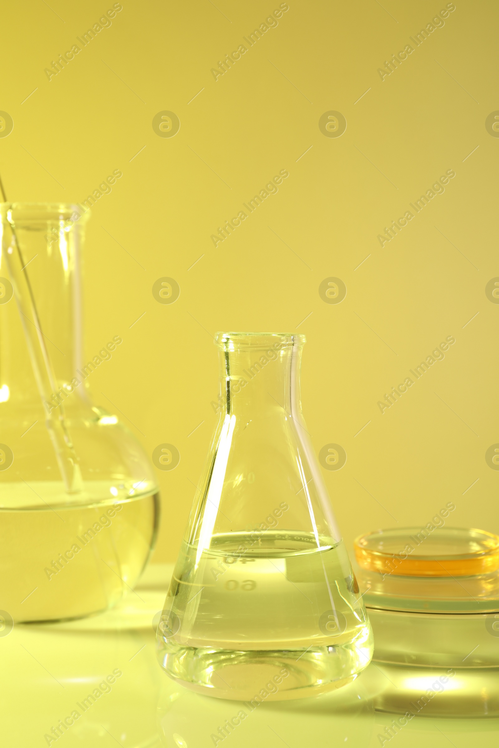 Photo of Laboratory analysis. Different glassware on table against yellow background