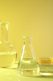 Photo of Laboratory analysis. Different glassware on table against yellow background