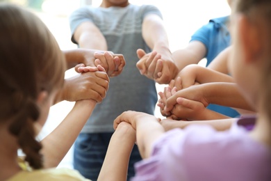 Photo of Little children holding their hands together, closeup. Unity concept