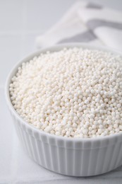 Photo of Tapioca pearls in bowl on white tiled table, closeup