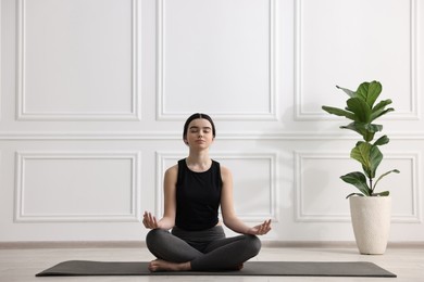 Beautiful girl meditating on mat in yoga studio