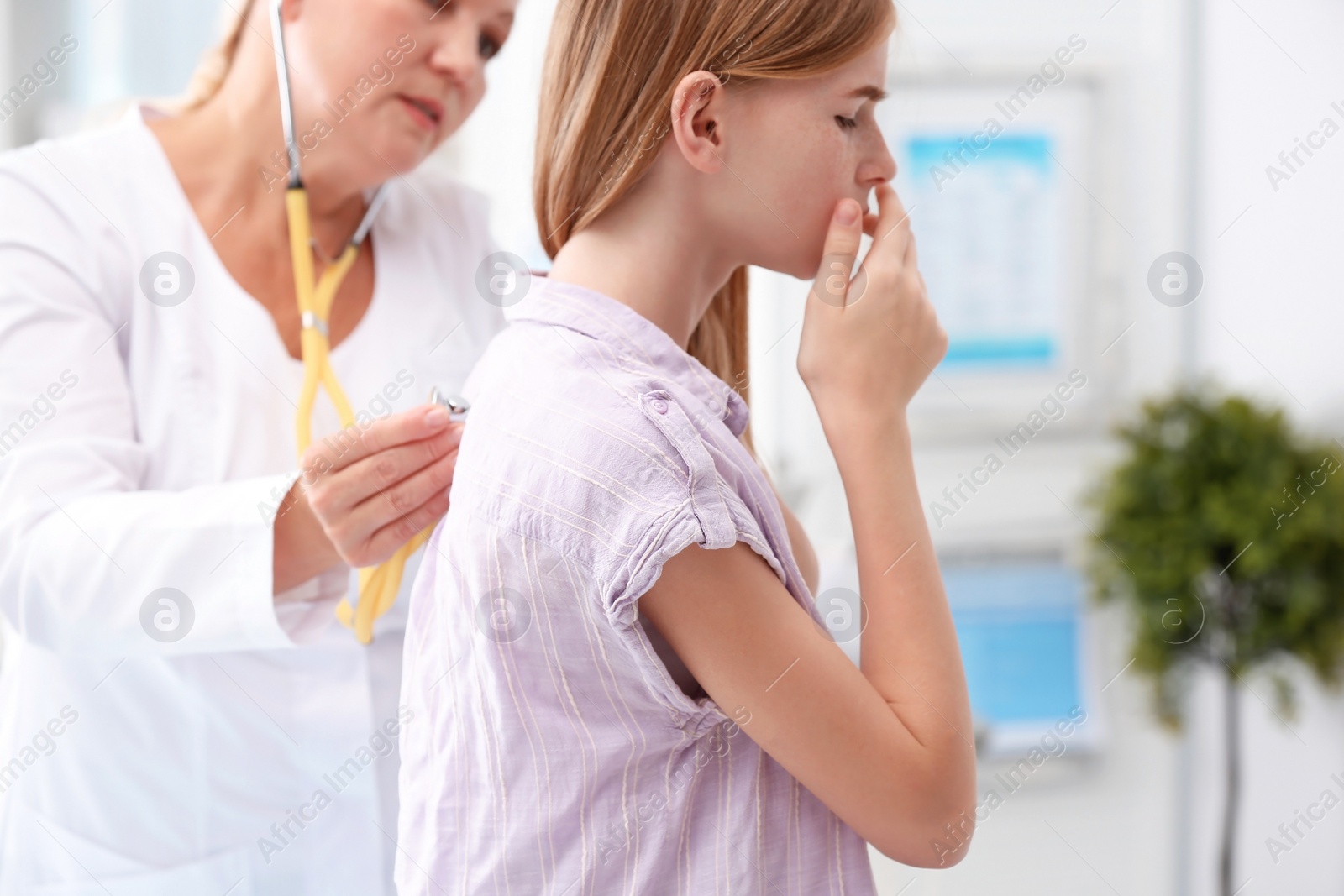 Photo of Doctor examining coughing teenage girl at clinic