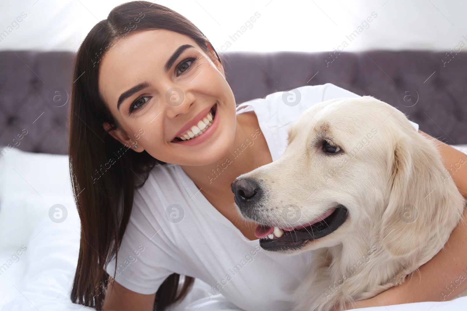 Photo of Young woman and her Golden Retriever dog on bed at home