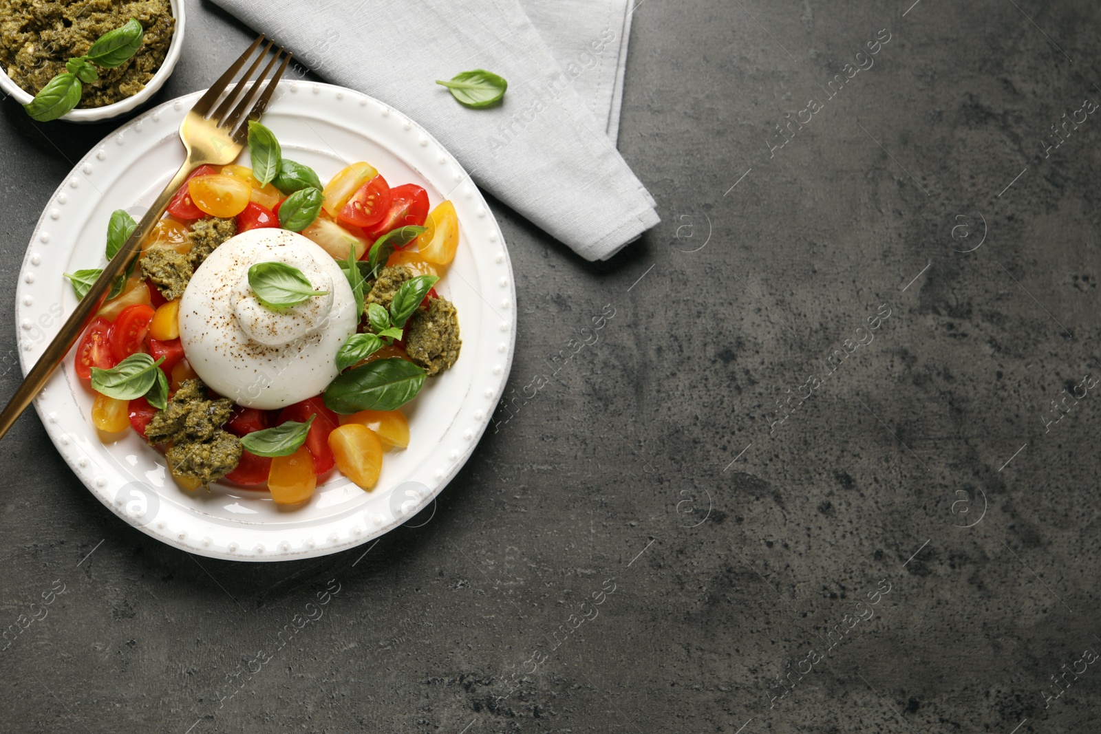 Photo of Delicious burrata salad served on grey table, flat lay. Space for text