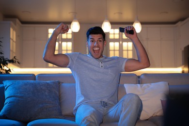 Excited man watching movie on sofa at night