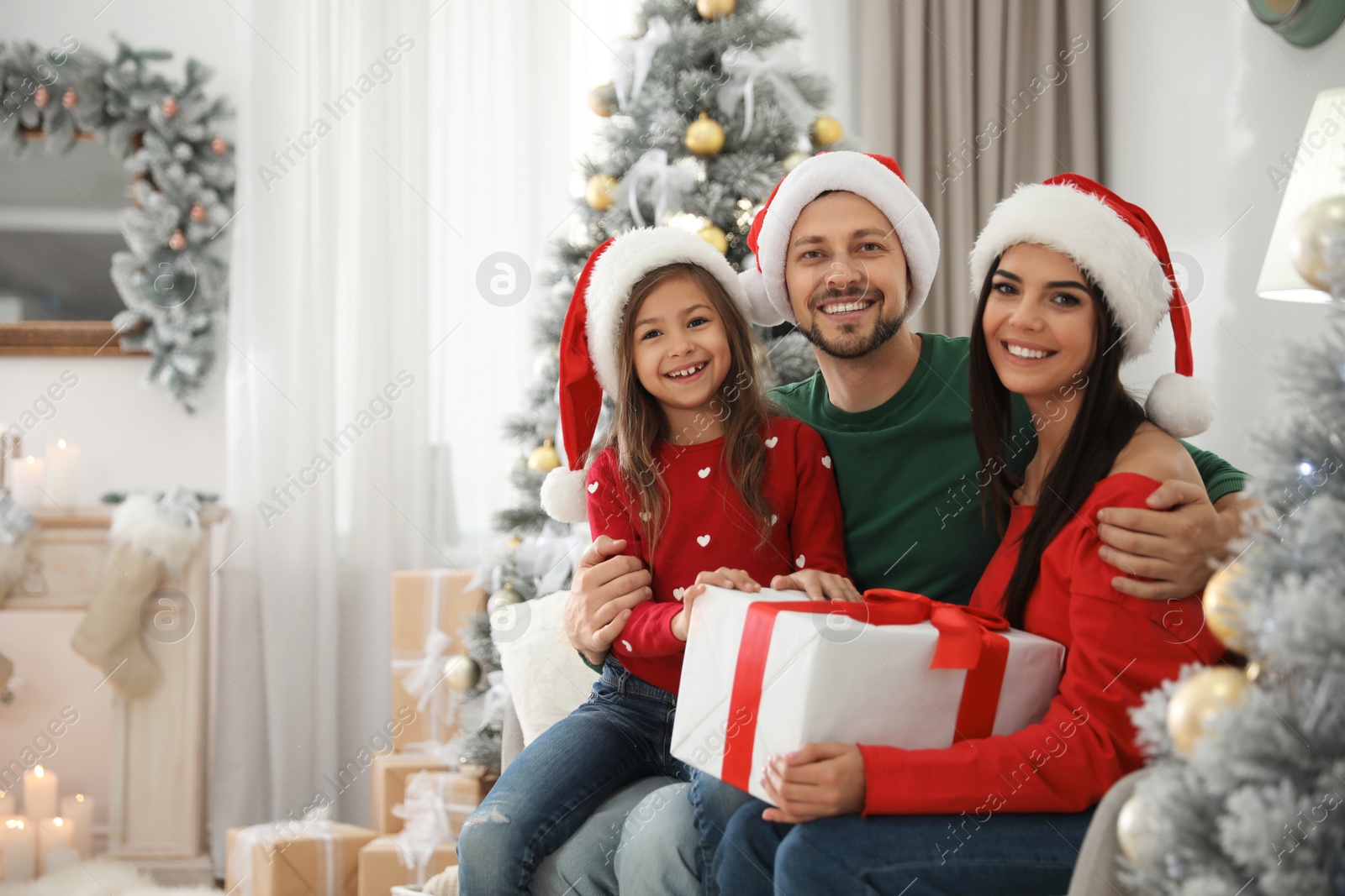 Photo of Portrait of happy family with Christmas gift at home, space for text