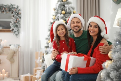 Photo of Portrait of happy family with Christmas gift at home, space for text