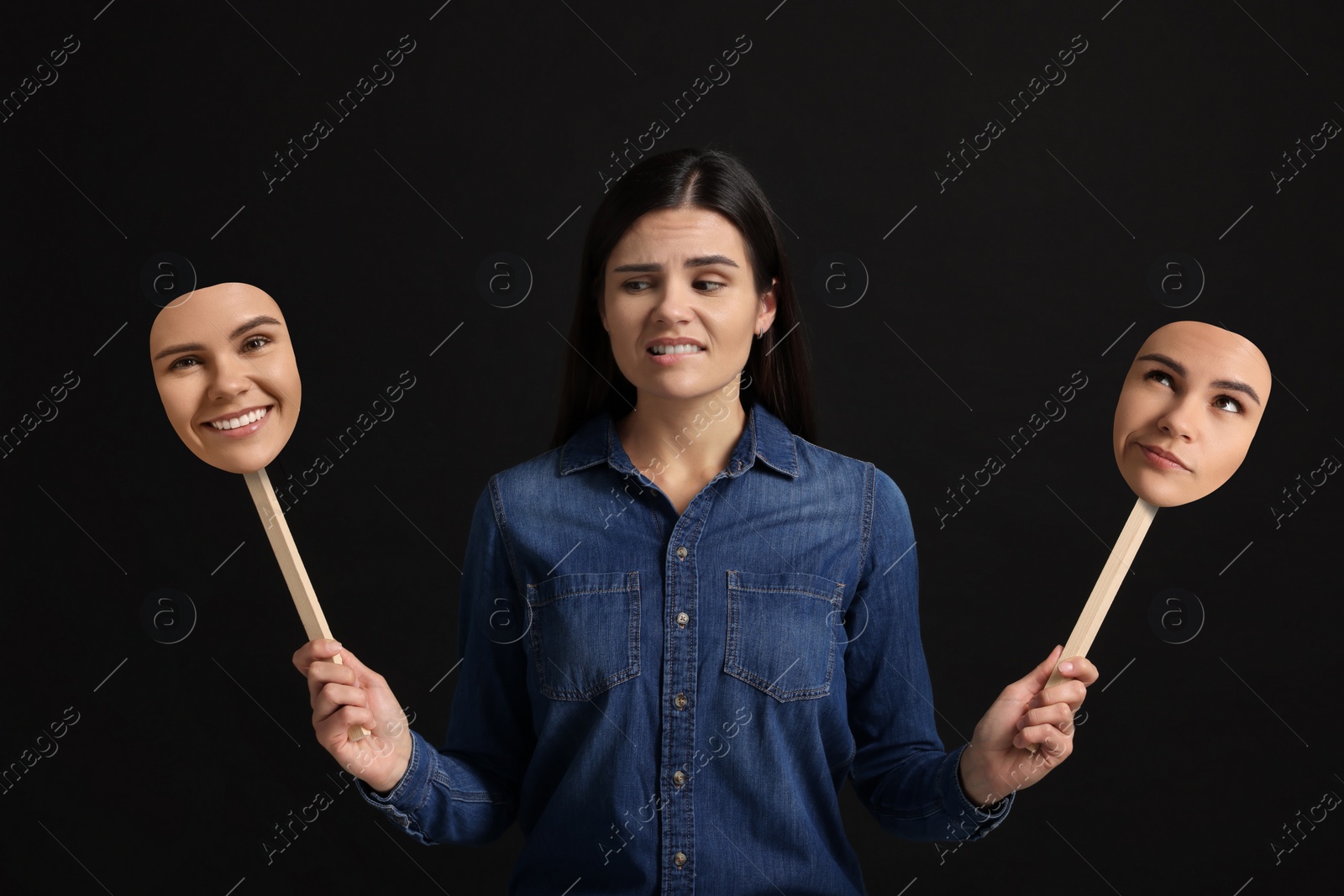 Image of Woman holding masks with her face showing different emotions on black background. Balanced personality