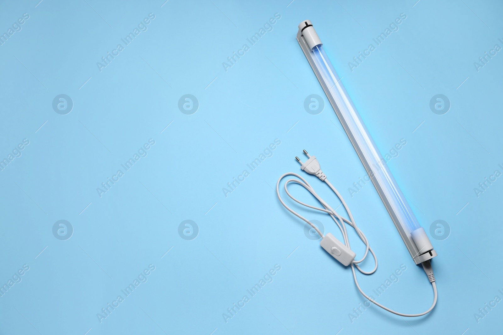 Photo of Ultraviolet lamp on light blue background, top view. Space for text