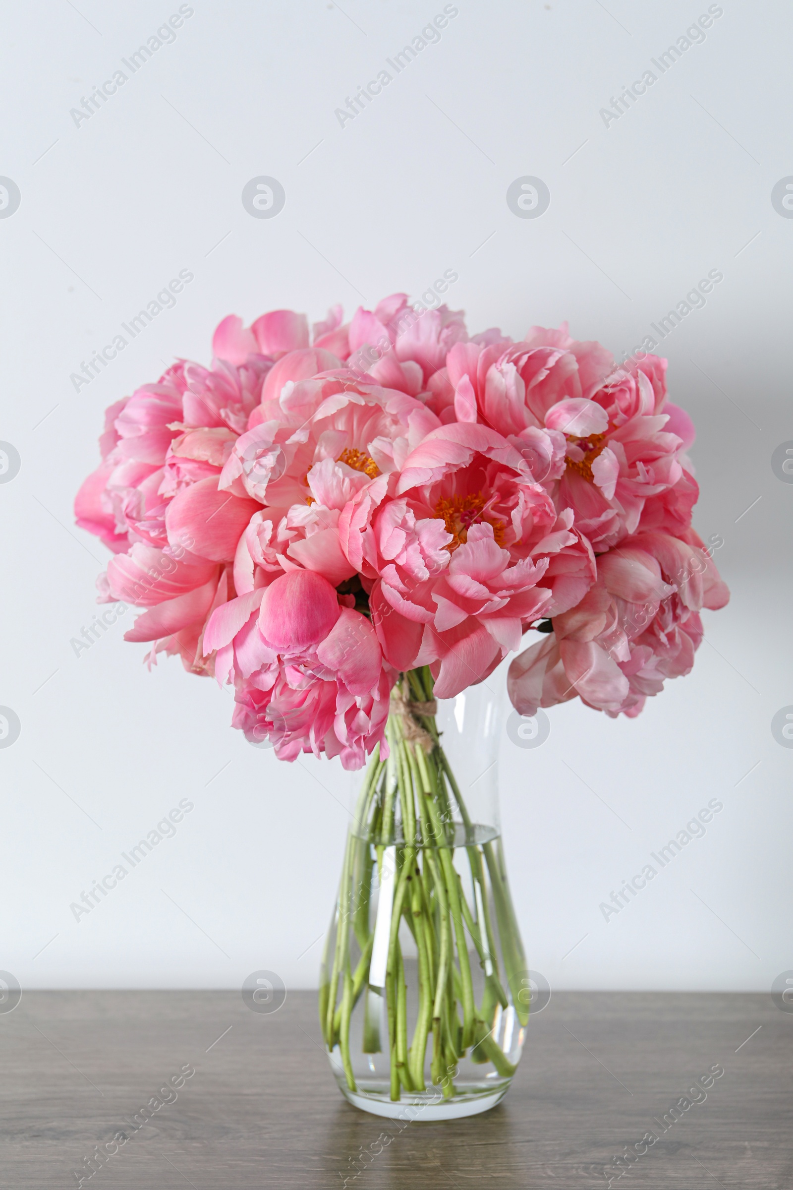 Photo of Beautiful bouquet of pink peonies in vase on wooden table against white background