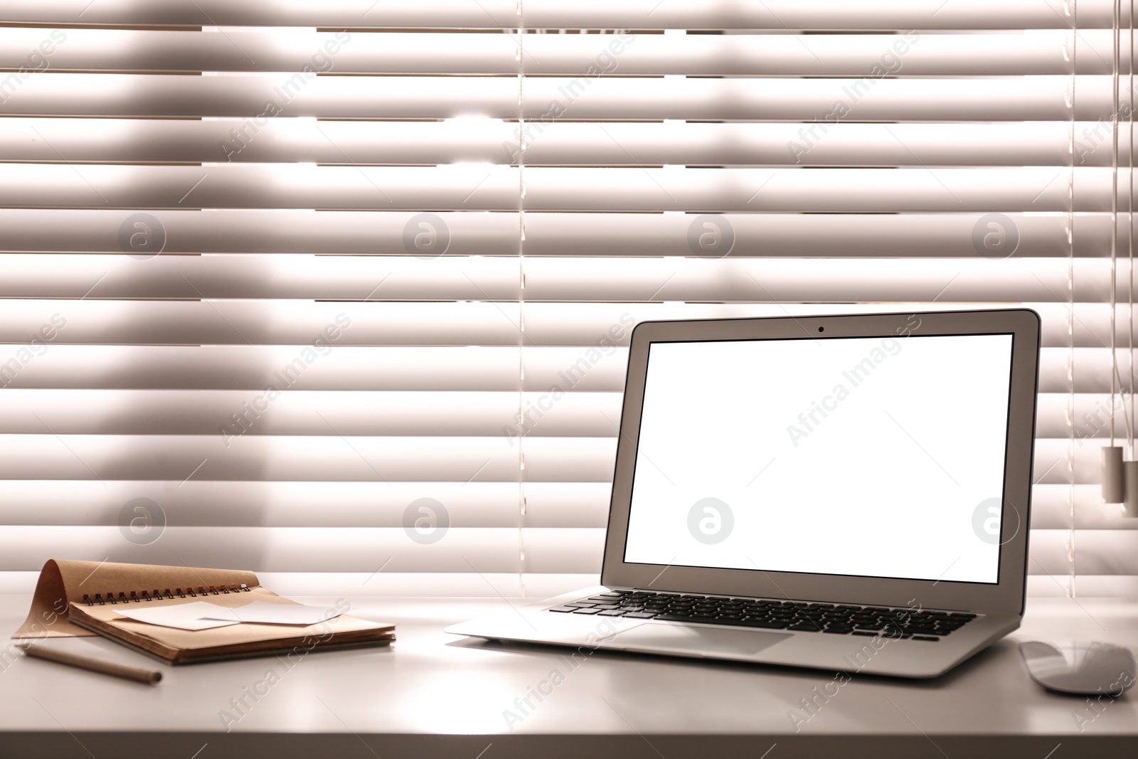 Photo of Laptop on desk near window in office. Comfortable workplace