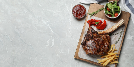 Flat lay composition with delicious grilled ribeye steak on light grey marble table, space for text. Banner design