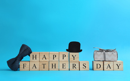 Photo of Wooden cubes with phrase HAPPY FATHER'S DAY on light blue background