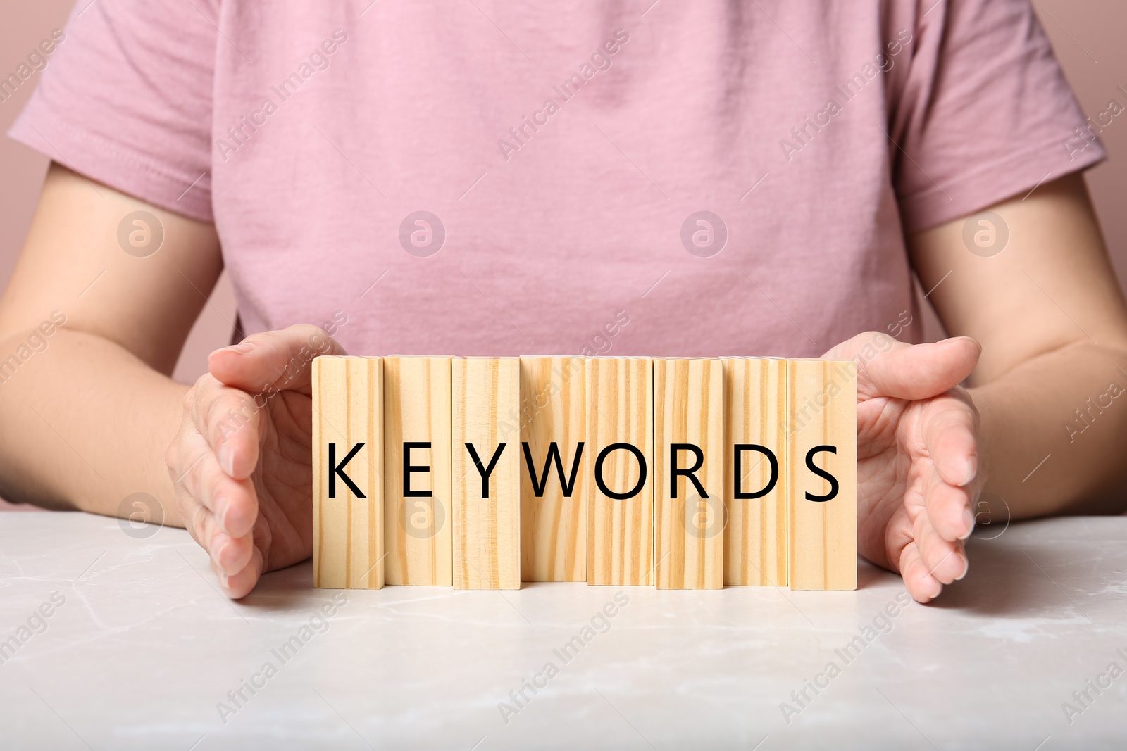 Photo of Woman demonstrating blocks with word KEYWORDS at grey marble table, closeup