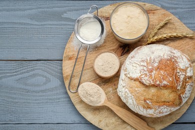 Photo of Freshly baked bread, sourdough and flour on grey wooden table, top view. Space for text