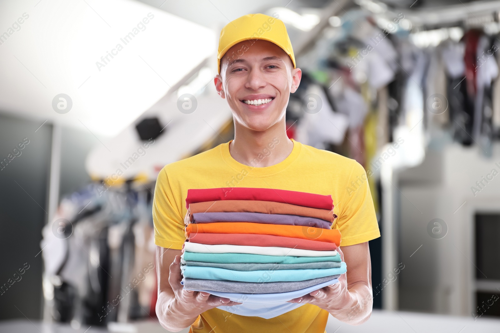 Image of Happy courier holding folded clothes in dry-cleaning