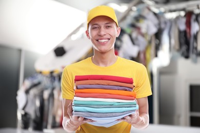 Happy courier holding folded clothes in dry-cleaning