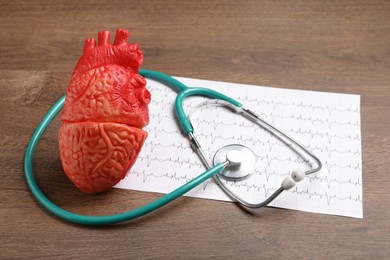 Stethoscope, cardiogram and heart model on wooden background. Cardiology concept