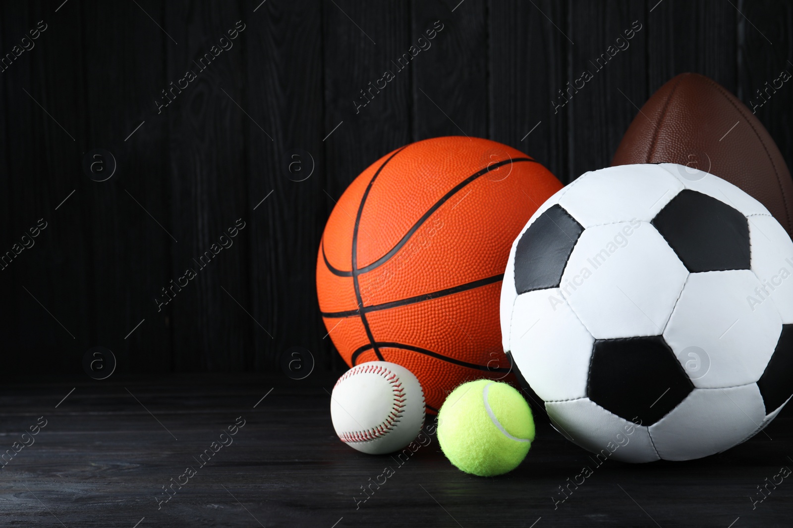 Photo of Set of different sport balls on black wooden table. Space for text