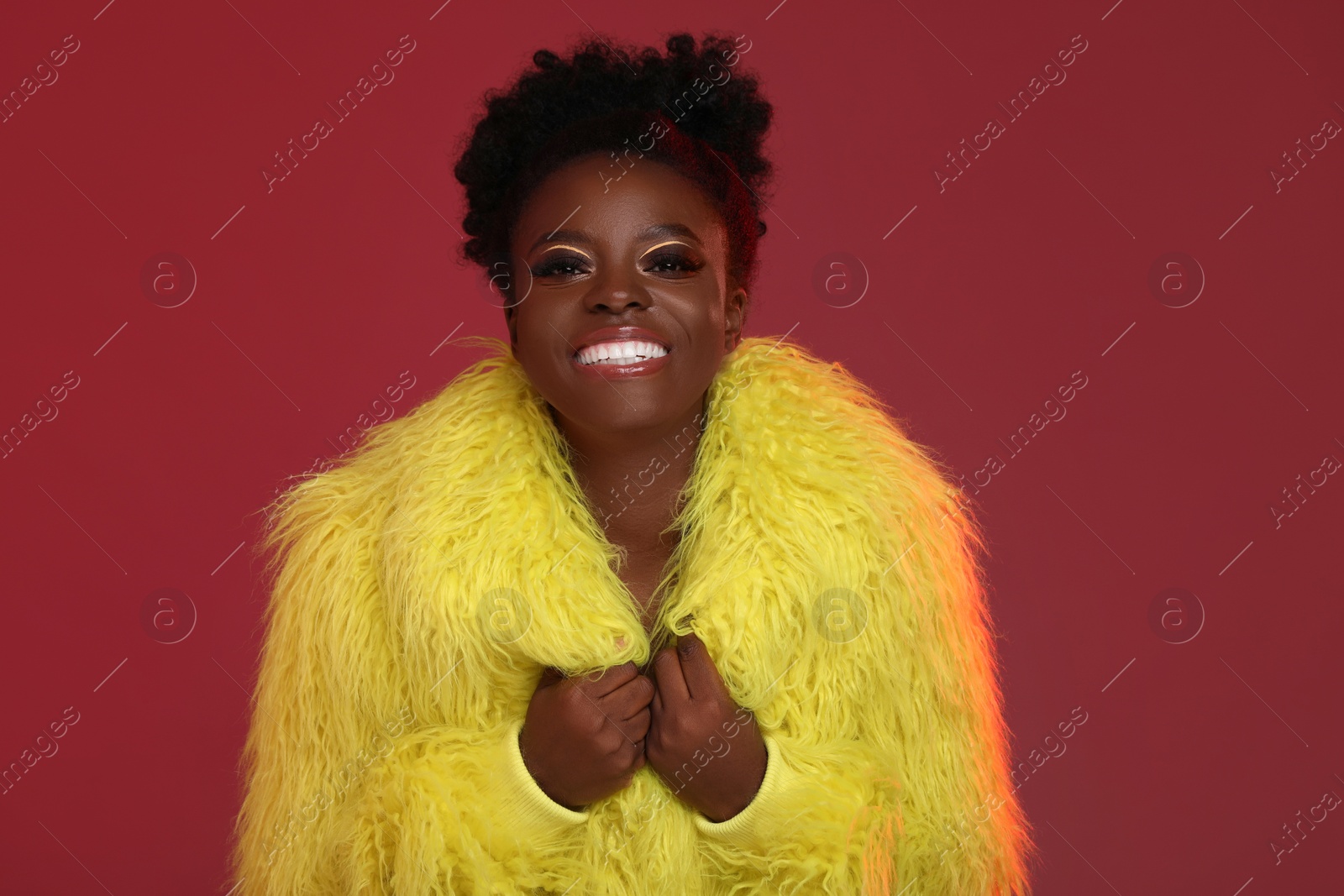 Photo of Fashionable portrait of beautiful happy woman with bright makeup on burgundy background