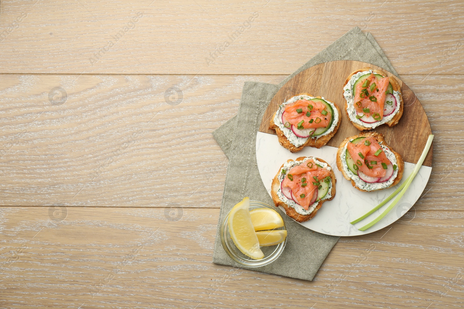 Photo of Tasty canapes with salmon served on wooden table, top view. Space for text