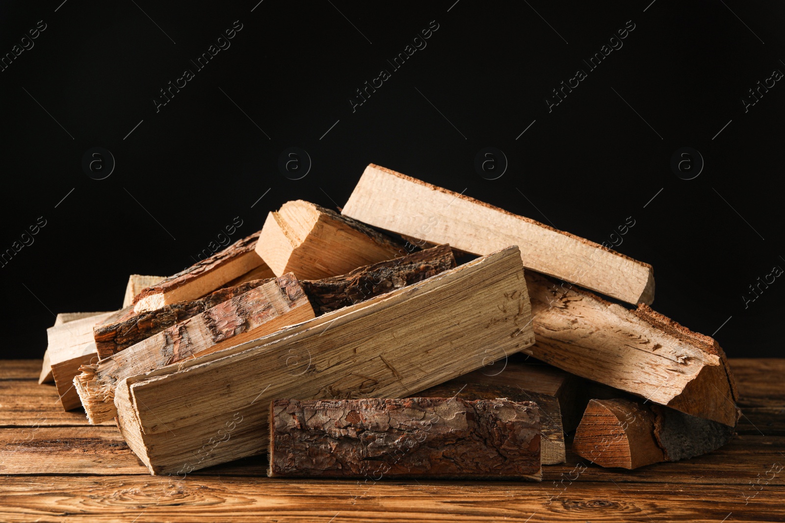 Photo of Cut firewood on table against black background