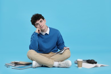 Portrait of student with notebook and stationery on light blue background