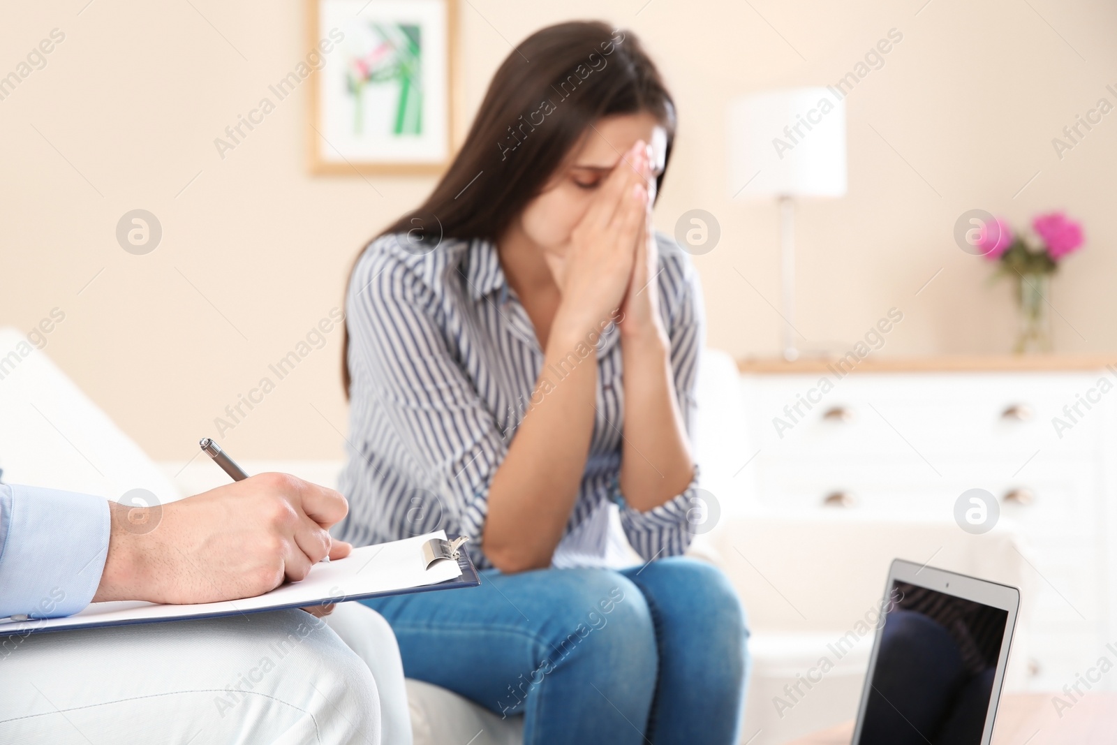 Photo of Depressed young woman having appointment with psychologist in office