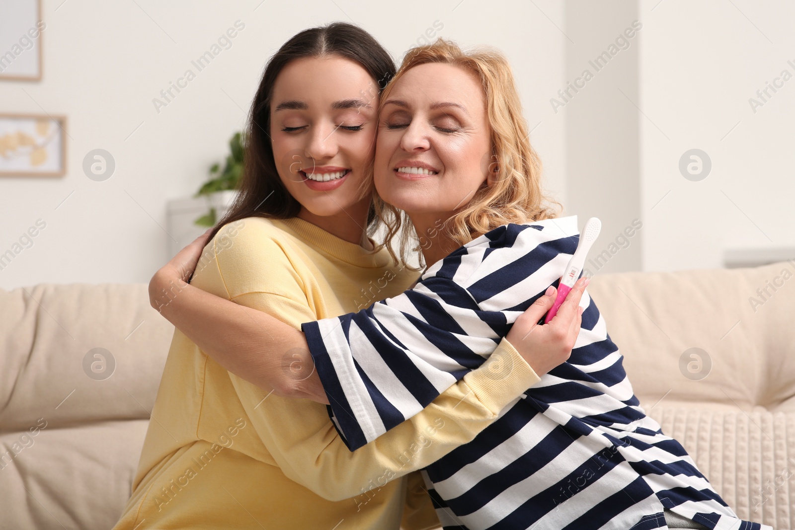 Photo of Happy pregnant woman spending time with her mother at home. Grandparents' reaction to future grandson