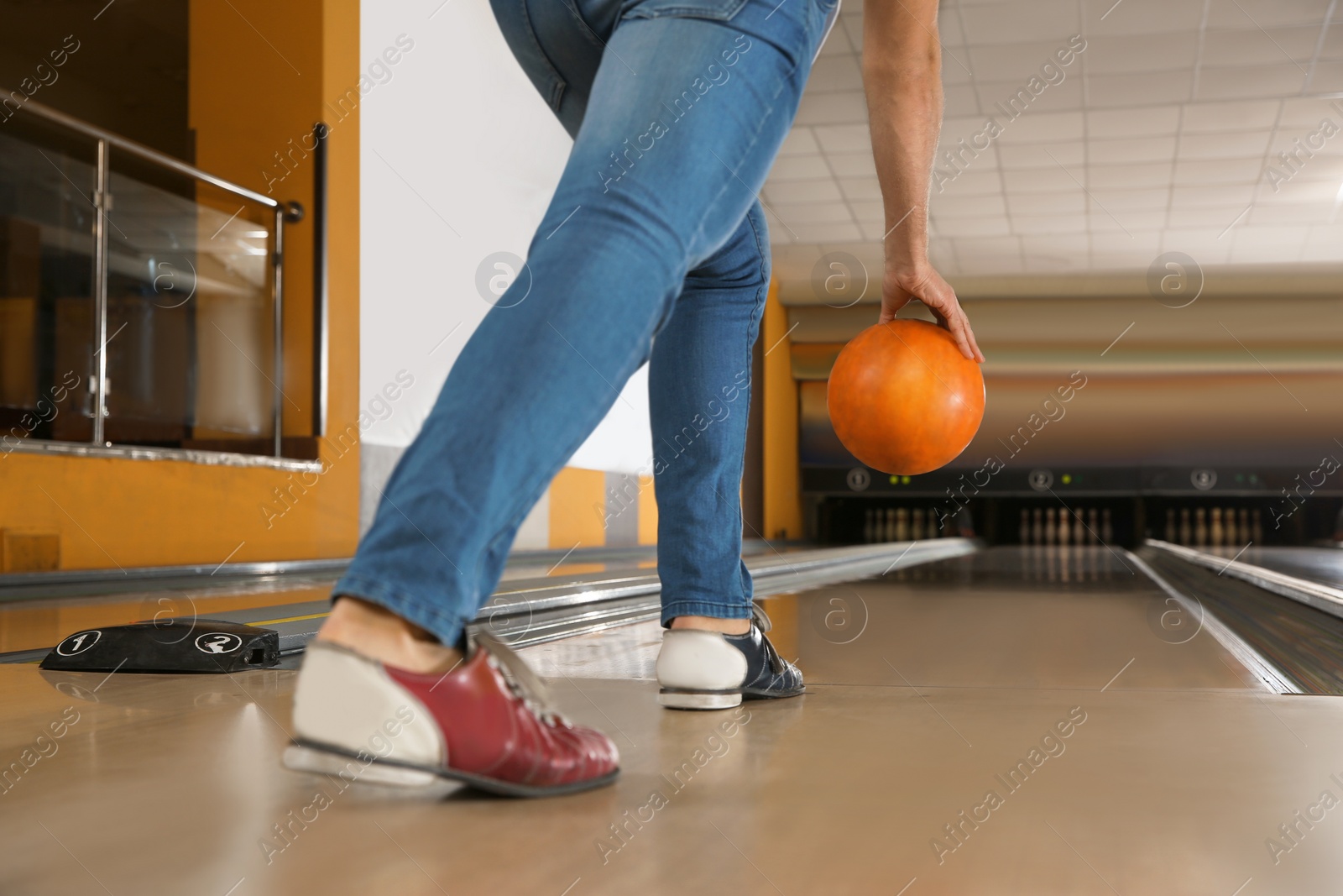 Photo of Young man throwing ball in bowling club, closeup