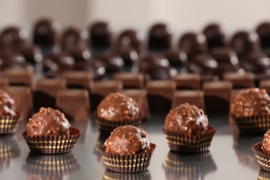 Many delicious chocolate candies on grey table. Production line