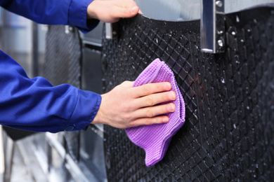 Photo of Worker wiping automobile floor mat at car wash, closeup