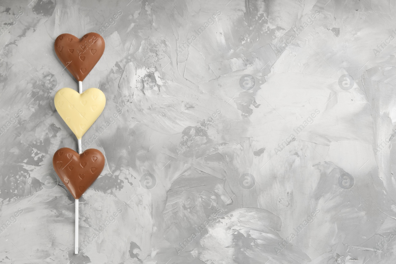 Photo of Different chocolate heart shaped lollipops on table, flat lay. Space for text