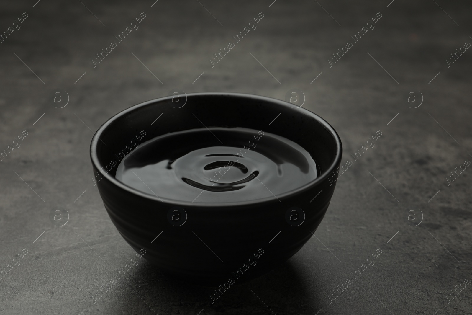 Photo of Black bowl with water on grey table