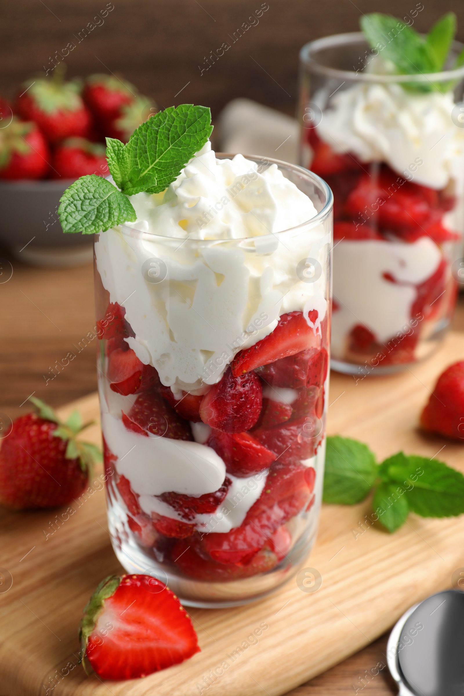 Photo of Delicious strawberries with whipped cream served on wooden table