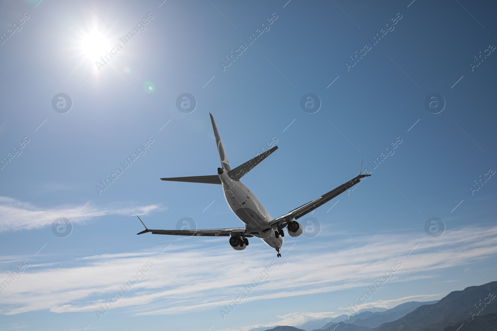 Photo of Modern white airplane flying in sky near mountains