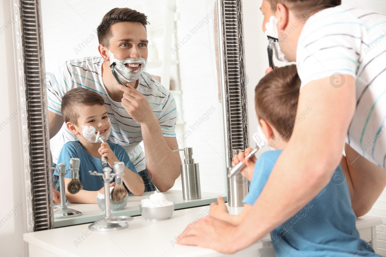 Photo of Dad shaving and little son imitating him in bathroom